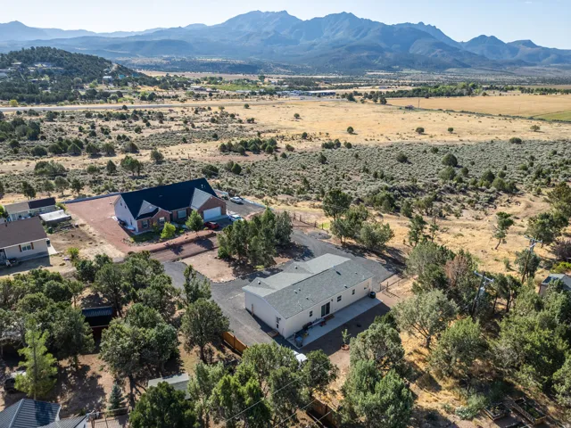 Expansive property featuring two distinct structures, surrounding mature trees, and a mountain backdrop