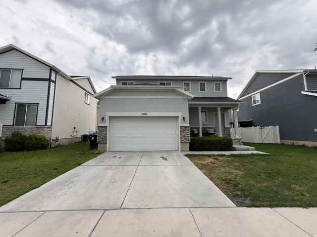 Two-story property with an attached garage, stone accents, and a covered porch with pillars