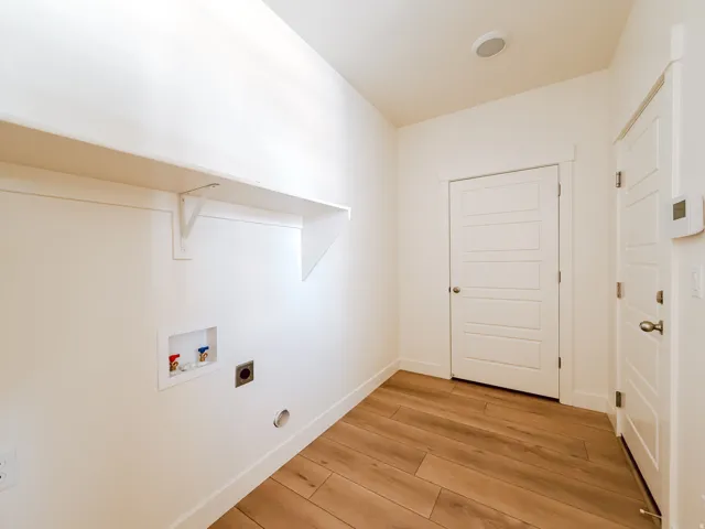 Spacious utility area featuring wood-finish flooring, built-in shelving, and a panel door