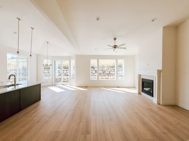 Open-concept living area with wood-finish flooring, a fireplace featuring a tile surround and white mantel, and a kitchen island with a dark base and light-colored countertop