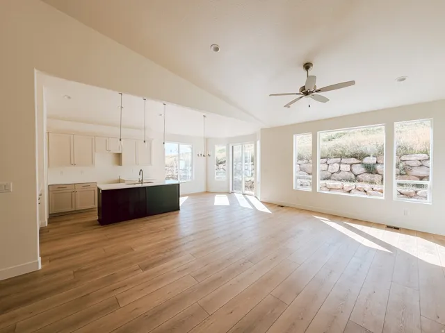 Spacious living area featuring wood-finish flooring, vaulted ceilings, and large windows