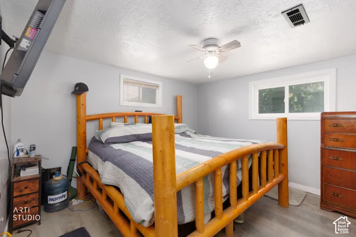 Gray wall paint, wood-finish flooring, white window trim, and a ceiling-mounted fan with light fixture
