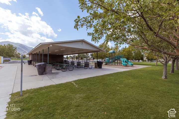 Covered picnic area with multiple tables and benches, surrounded by a manicured lawn