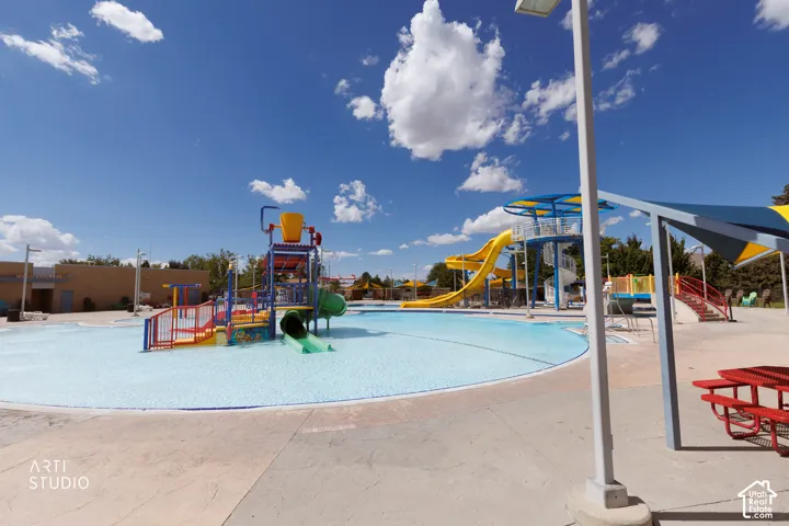 Curved pool with a light blue finish, featuring multiple water slides and a water play structure