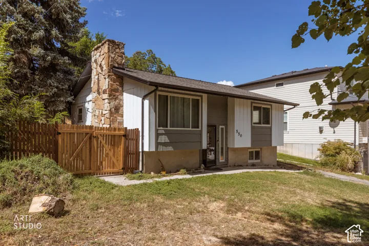 Split-level exterior with a stone chimney, wood fence
