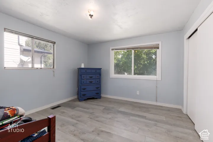 Wood-finish flooring, two windows, and a built-in closet with sliding doors