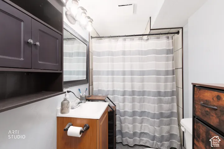 Bathroom featuring a vanity with a white countertop, wall-mounted mirror, overhead lighting fixture, and a built-in wall cabinet with shelving