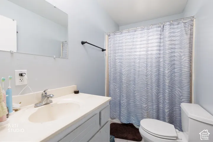 Bathroom featuring a vanity with an integrated sink, wall-mounted mirror, and a toilet