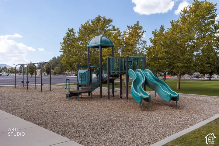 Playground featuring a swing set, multi-level play structure, and dual slides on a wood chip surface