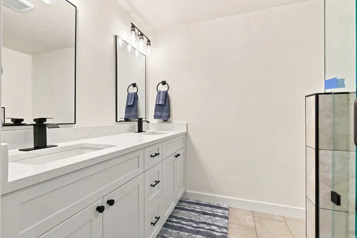 Master Bath, dual sink vanity with white cabinetry, matte black hardware, stone-look countertops, and rectangular mirrors