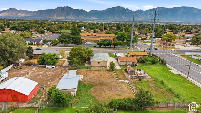 Expansive lot with distant mountain range, red barn structure, and mature trees