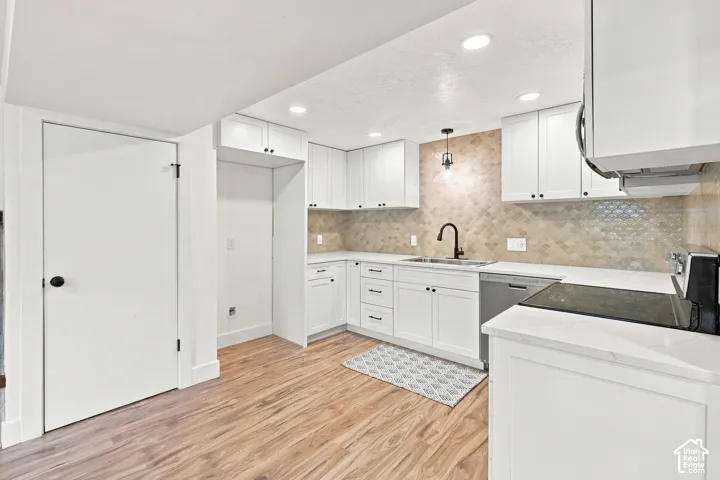 White cabinetry, light wood-finish flooring, light-colored backsplash, light countertops, and recessed lighting