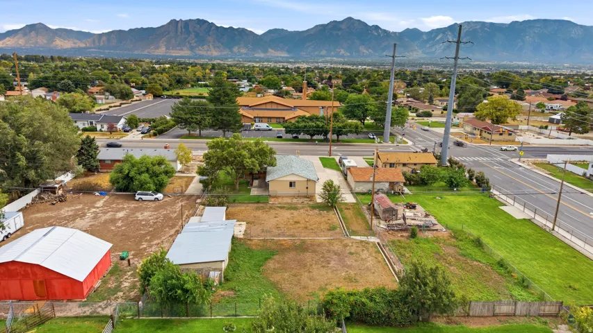 Expansive lot with distant mountain range, red barn structure, and mature trees