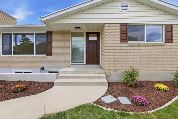 Brick exterior with white window trim and brown shutters, featuring a brown entry door with a frosted glass panel. Prior to handrail installation.