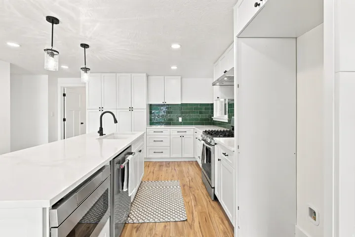 Kitchen featuring white cabinetry, wood-finish flooring, and a green tile backsplash