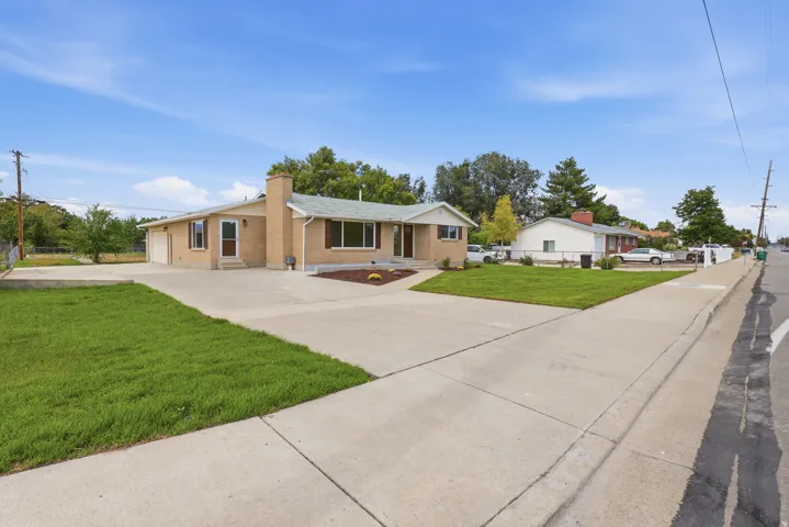 Brick exterior residence with a concrete driveway and sidewalk, featuring a landscaped front yard with grass and plantings