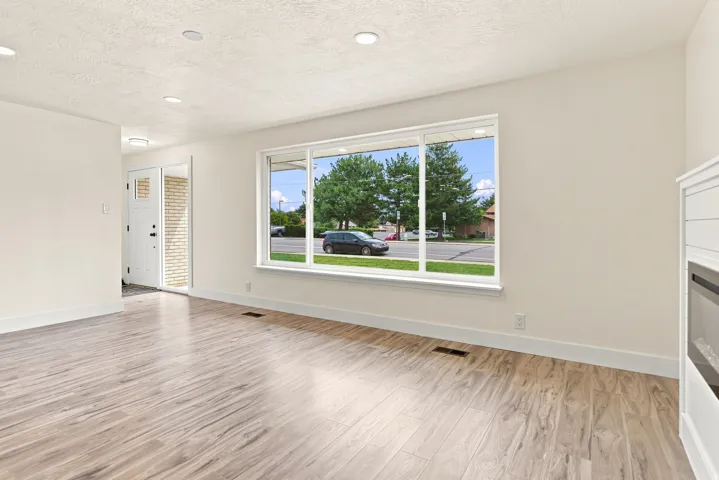 Wood-finish flooring, recessed lighting, and a large picture window provide ample illumination