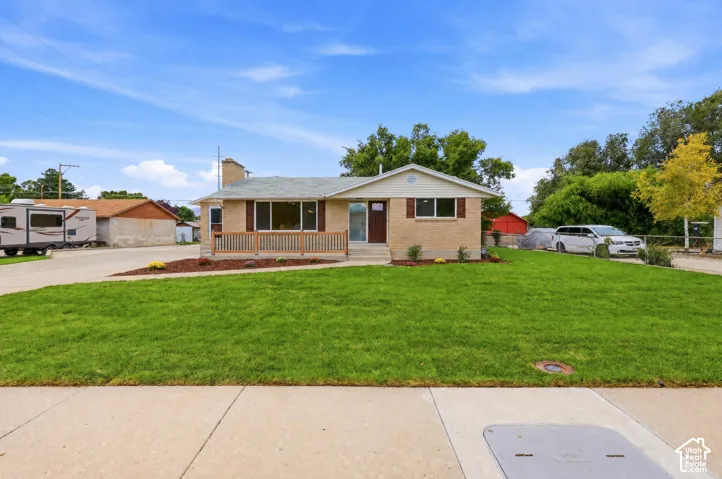 Curb appeal featuring a manicured front lawn, brick and siding exterior, front porch with wood railings, and a concrete driveway