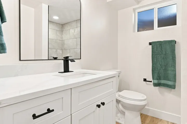 White vanity with shaker-style cabinetry, a built-in sink, and a black single-handle faucet