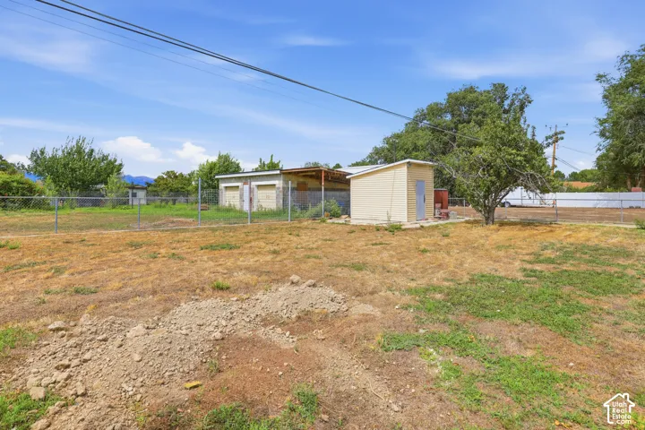 Expansive lot featuring a chain-link fence, various outbuildings, and mature trees