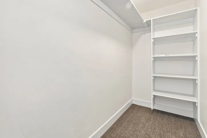 Built-in shelving unit providing storage, neutral wall finishes, and patterned carpeting
