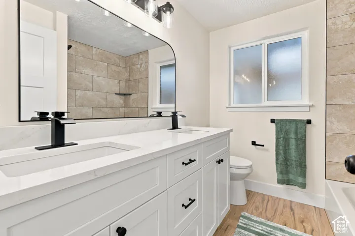 Full Bath with double vanity with integrated rectangular sinks, white cabinetry, matte black hardware, and a white countertop and bathtub shower