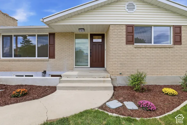 Brick exterior with white window trim and brown shutters, featuring a brown entry door with a frosted glass panel. Prior to handrail installation.