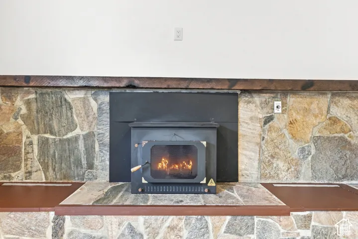 Wood-burning stove set within a stone-clad fireplace, featuring a raised stone hearth and integrated wood-finish benches.  Staged fire in this photo.
