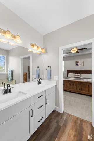 Dual vanity with undermount sinks, white countertops, black matte faucets, and wood-finish flooring