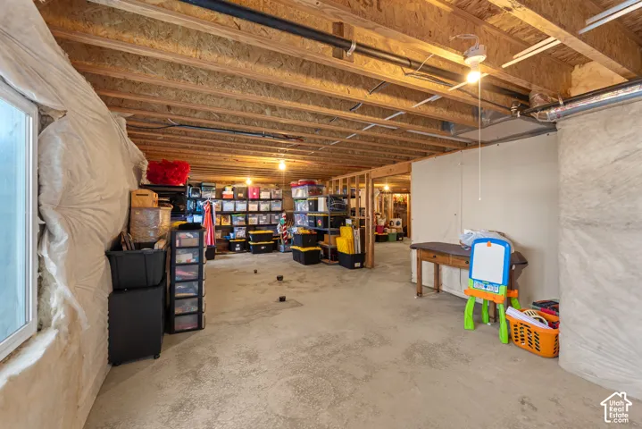 Unfinished basement featuring exposed wood joists, concrete flooring, and partial insulation