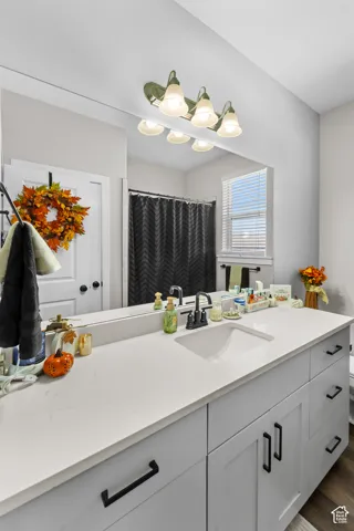 Dual-sink vanity with a light-toned countertop, matte black hardware, integrated rectangular sink, and a large wall-mounted mirror