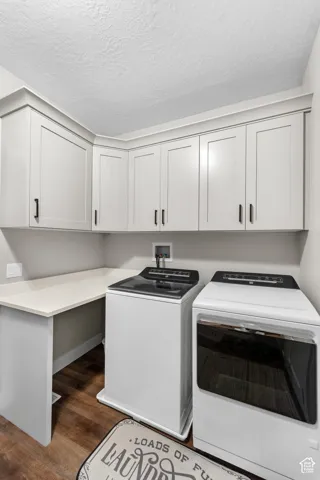 Laundry area featuring wood-finish flooring, white cabinetry, integrated countertop, and matte black hardware