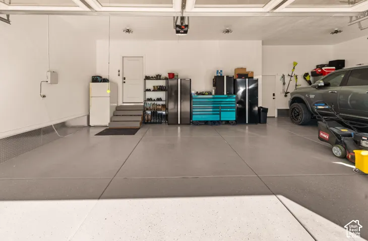 Spacious garage with light gray finished flooring, white walls, and overhead lighting