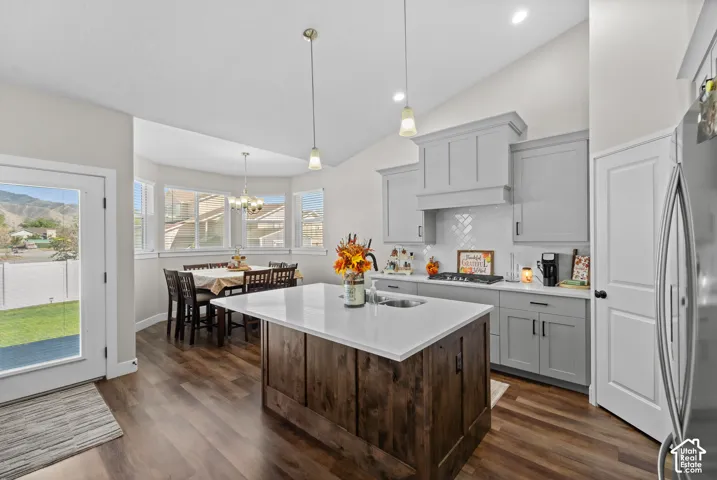 Spacious kitchen featuring an expansive center island with countertop seating, wood-finish flooring, light gray cabinetry, and a white subway tile backsplash