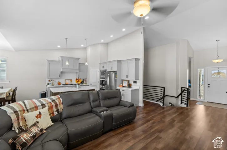 Spacious open-concept living area featuring wood-finish flooring, vaulted ceilings, and recessed lighting