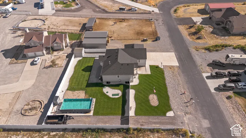 L-Shaped lot features horse area plus green family area. Expansive green lawn, fenced outdoor swimming pool, paved driveway, detached outbuilding, and a two-story residence with a dark shingle roof