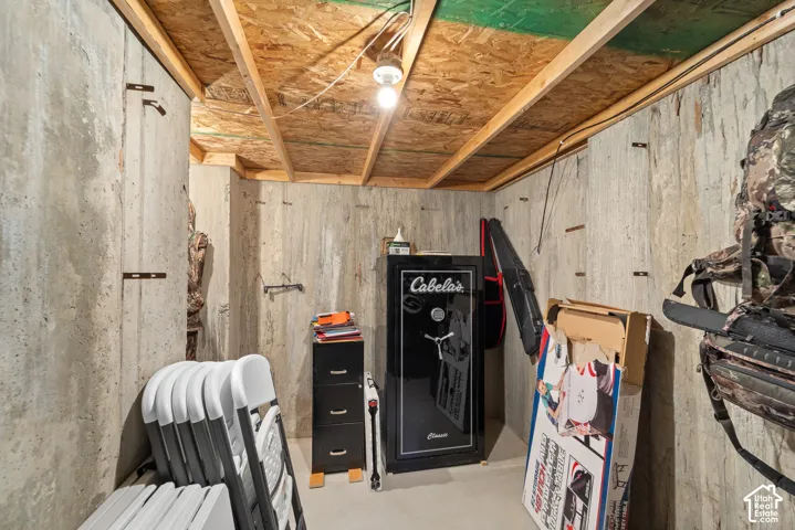 Exposed ceiling joists with plywood sheathing, concrete block walls, and concrete flooring