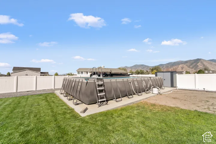 Expansive backyard featuring a manicured lawn, an above-ground pool, and white privacy fencing