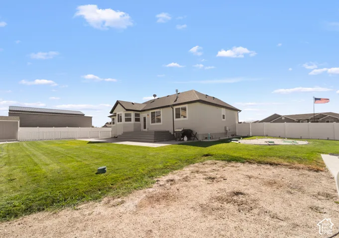 Expansive backyard with a manicured lawn, a white privacy fence, and a concrete patio