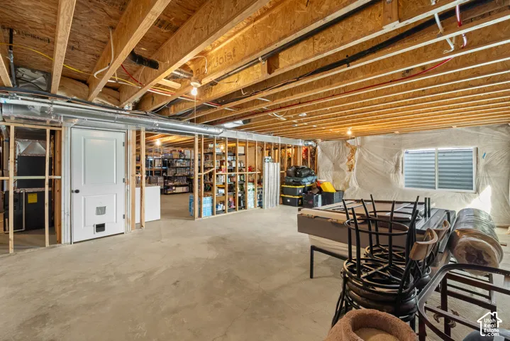 Expansive unfinished basement with exposed wood-beam ceiling, recessed lighting, and concrete flooring