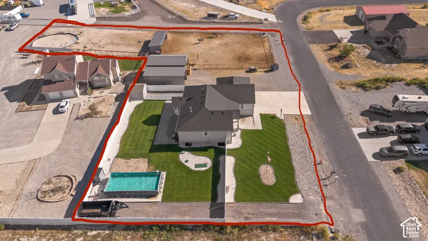 Rectangular swimming pool, manicured lawn, paved patio, gravel landscaping, and a two-story residence