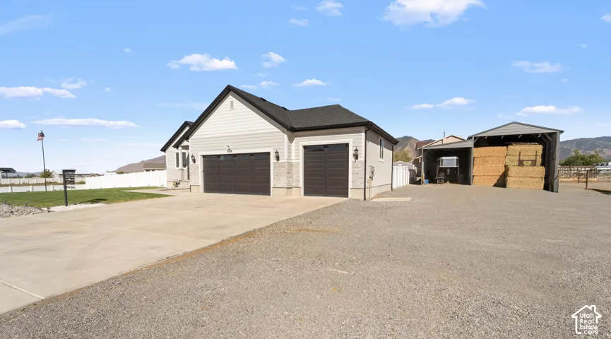 Attached two-car garage with dark wood-finish doors, light-colored siding exterior, gray stone accents, and exterior wall sconces
