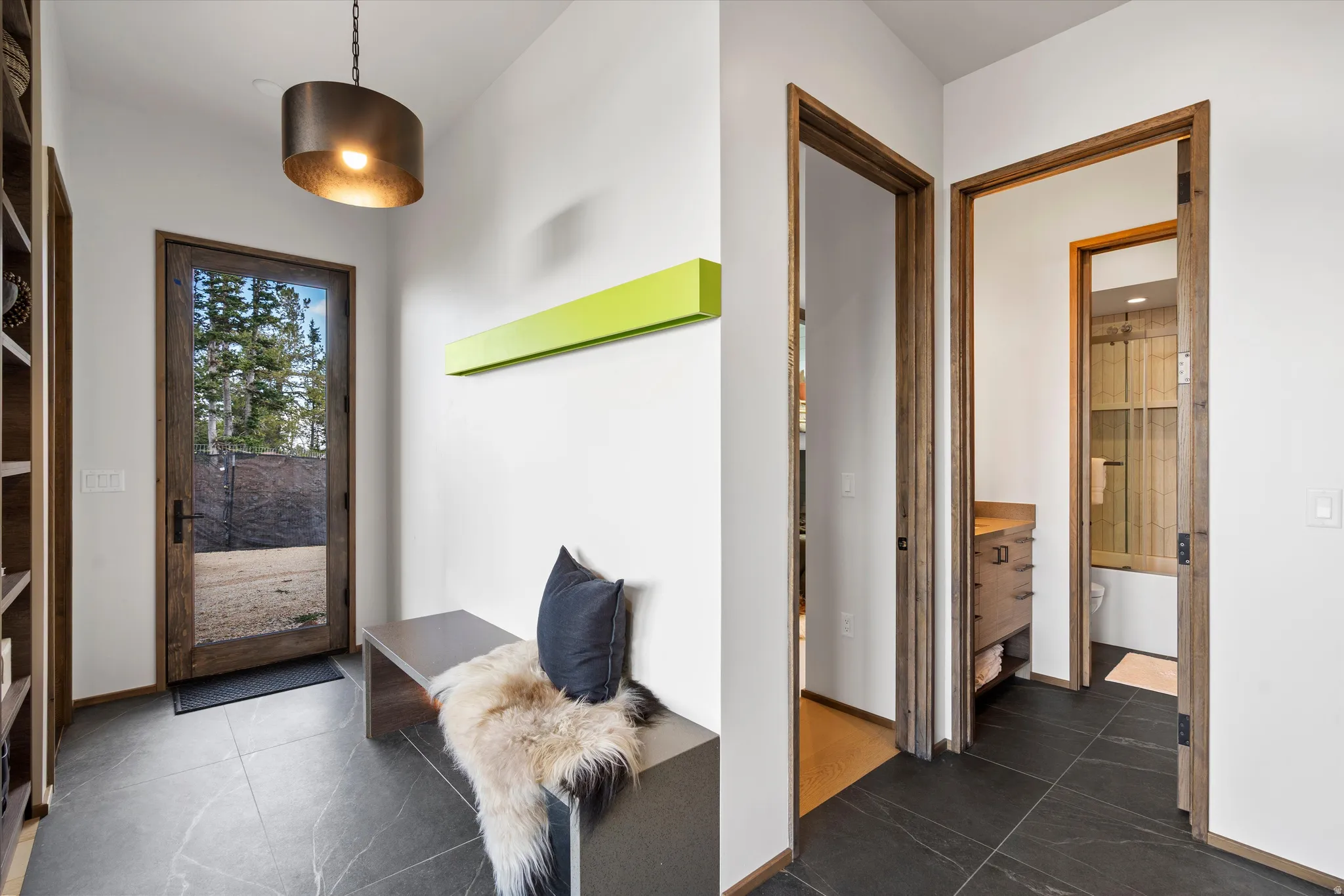 Entryway featuring large format dark tile flooring, a full-lite wood-frame door, and a built-in bench