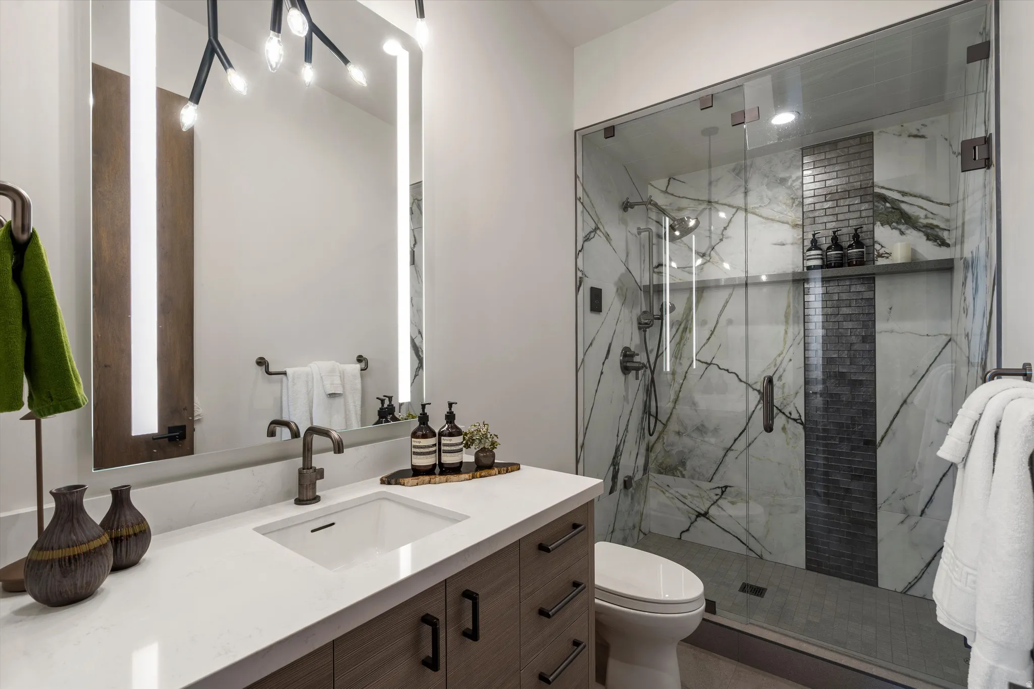 Contemporary bathroom featuring a floating wood-finish vanity with white quartz countertop, rectangular vessel sink, and matte black hardware