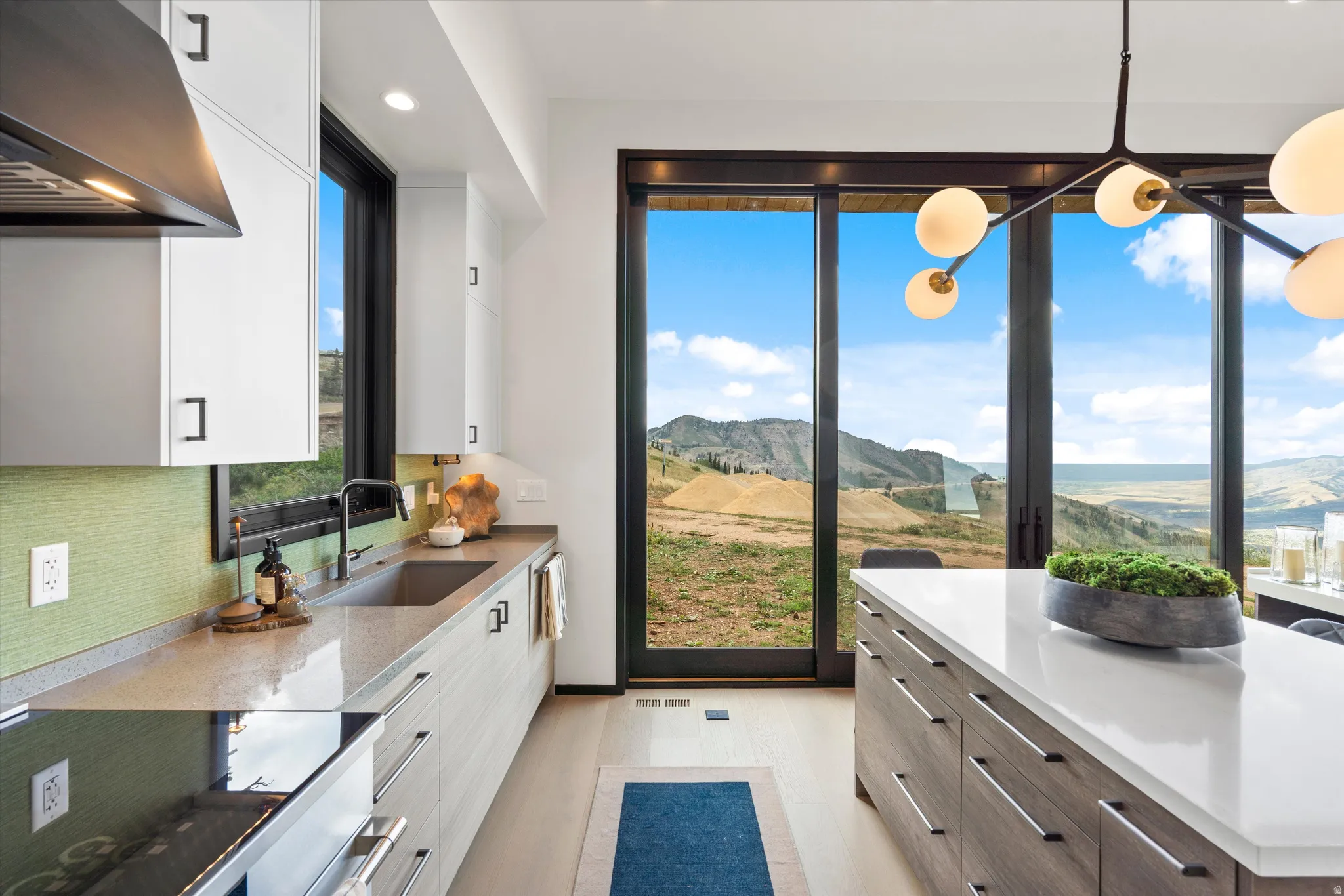 Modern kitchen with white cabinetry, a large center island with a white countertop, and expansive sliding glass doors