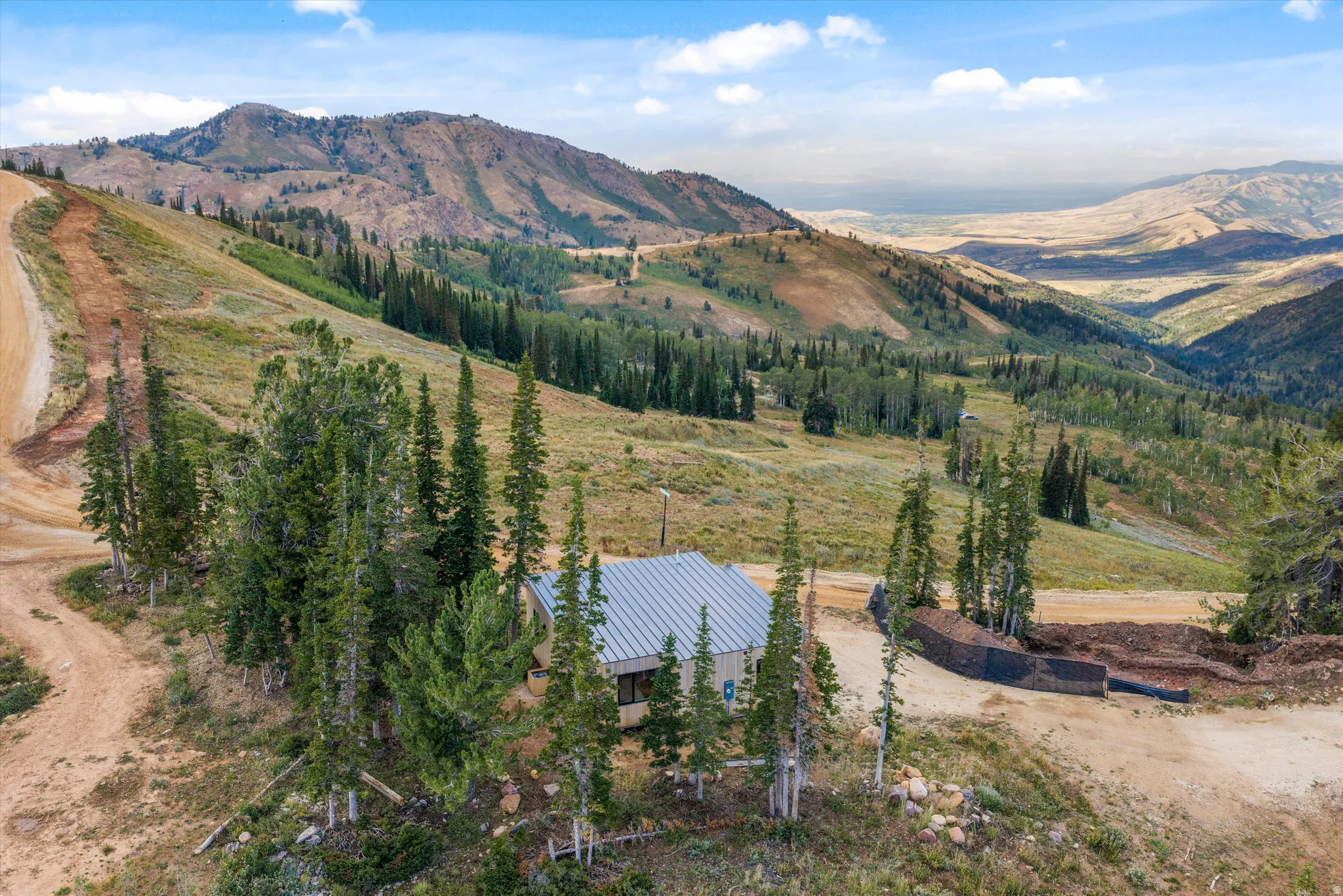 Mountainous terrain with natural landscaping, a pitched roof structure, and surrounding evergreen trees