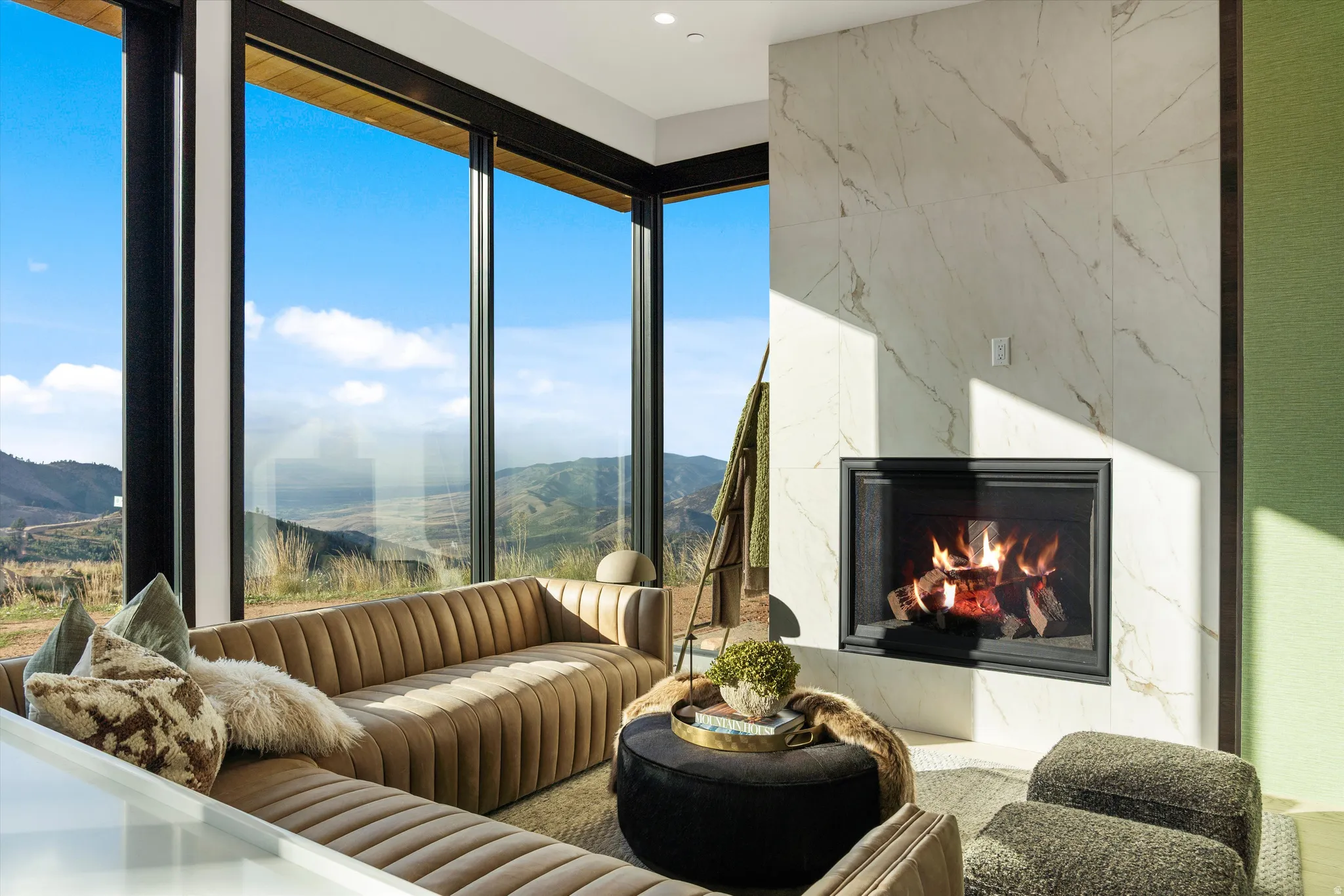 Full-height windows, a built-in fireplace with a stone-finish surround, and recessed ceiling lighting