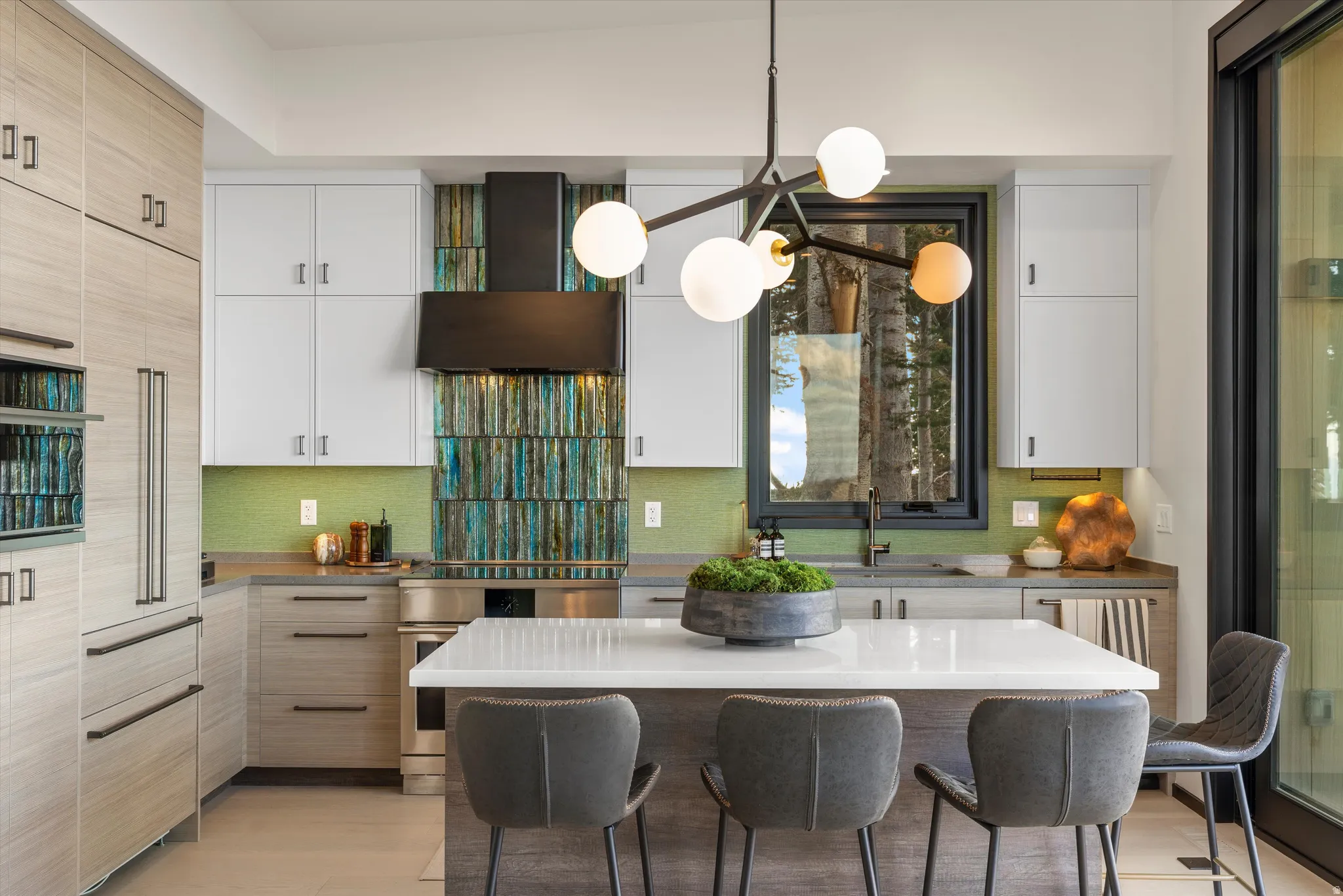 Modern kitchen with integrated stainless-steel appliances, a white island countertop, a decorative tiled backsplash, and a contemporary light fixture