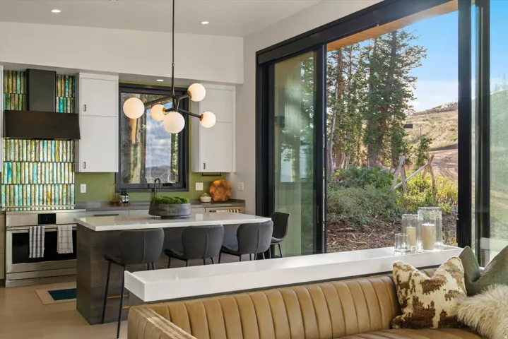 Kitchen featuring a large island with seating, stainless steel appliances, a unique tile backsplash, and a modern chandelier