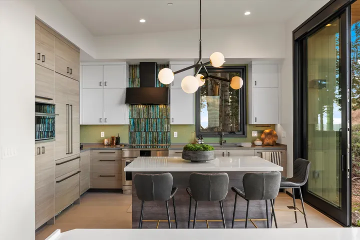 Contemporary kitchen featuring integrated appliances, a multi-tone tile backsplash, and a large center island with seating